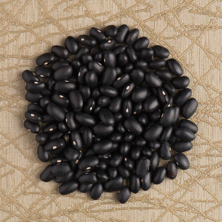 Circle of black beans on green vinyl background.