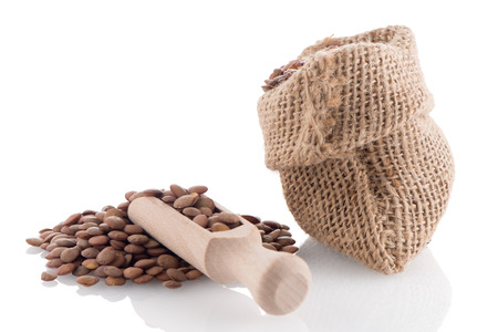 Burlap bag with lentils and wooden scoop on white background.の写真素材