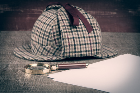 Deerstalker or Sherlock Hat and magnifying glass on Old Wooden table.の写真素材