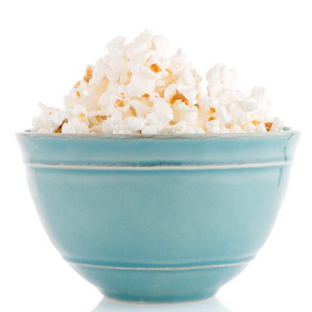 Popcorn in a blue bowl on a white backgroundの写真素材