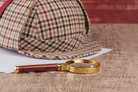 Deerstalker or Sherlock Hat and magnifying glass on Old Wooden table.の写真素材