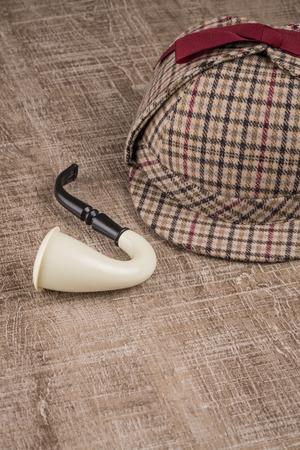Deerstalker or Sherlock Hat and Tobacco pipe on Old Wooden table.の写真素材