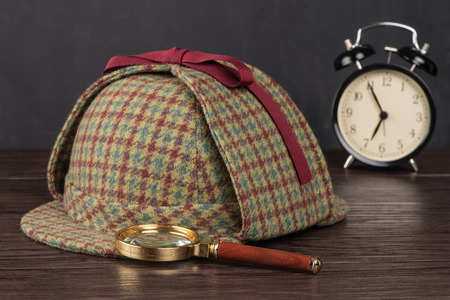 Deerstalker or Sherlock Hat and magnifying glass on Old Wooden table.の写真素材