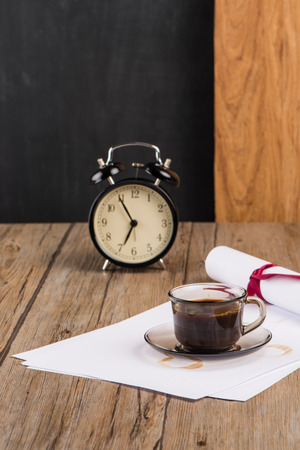 Old clock, hat, coffee and paper sheets on old Wooden table.の写真素材