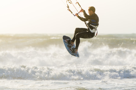Kitesurfer jumping on a beautiful background of spray during the sunset.の写真素材