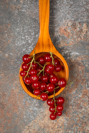 Currants in a wooden spoon on stone textured background.の写真素材