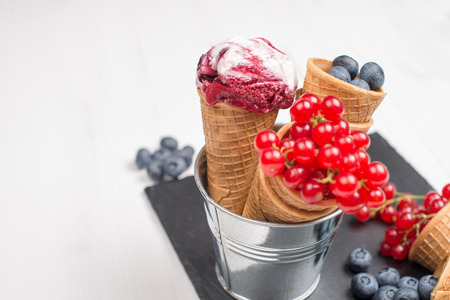 Red fruits ice cream cone on black slate board.の写真素材