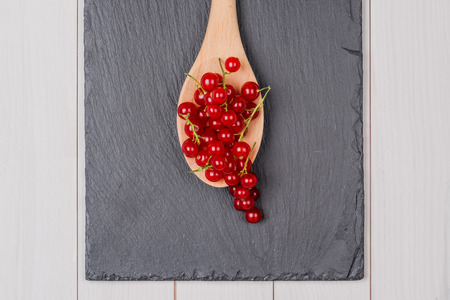 Currants in a wooden spoon on vintage wooden background.の写真素材