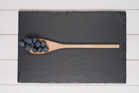 Blueberries on a wooden spoon against vintage wooden background.の写真素材