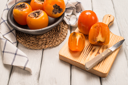 Delicious orange persimmons on wooden tableの写真素材