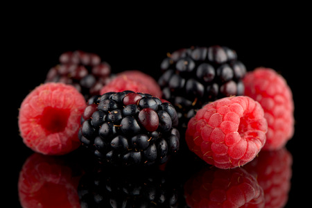 Composition from a blackberry and raspberry on the black isolated background