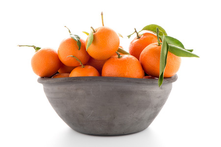 Tangerines on clay bowl isolated on white backgroundの写真素材