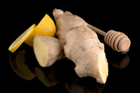 Ginger root drizzler with honey and lemon on black reflective background