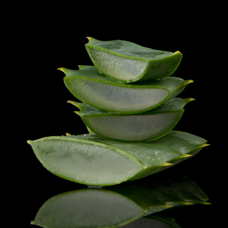 Sliced aloe leaf and water drops isolated on black background.の写真素材