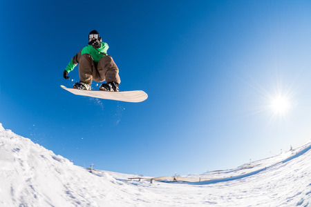 Snowboarder executing a radical jump against blue sky.の写真素材