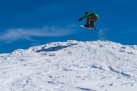 Snowboarder executing a radical jump against blue sky.の写真素材