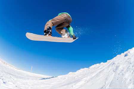 Snowboarder executing a radical jump against blue sky.の写真素材