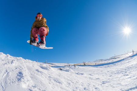 Snowboarder executing a radical jump against blue sky.の写真素材