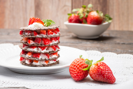 Strawberries desert with cream and wafer served on plate over table top.の写真素材