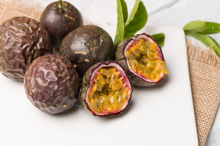 Passion fruits on white ceramic tray on wooden table background.
