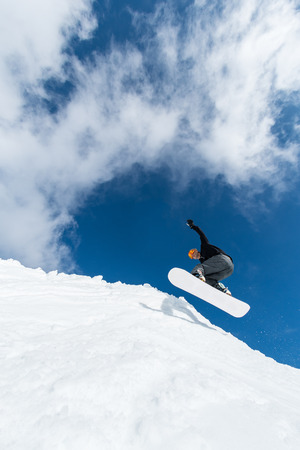 Snowboarder executing a radical jump against blue sky.の写真素材