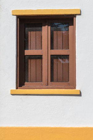 Traditional brown window on white wall.