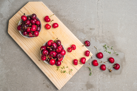 Red ripe cherries in ceramic bowls on kitchen countertop.の写真素材
