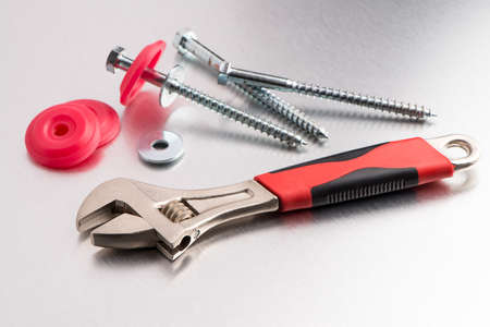 Spanner tool and screws on metal finish background.