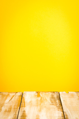 Wooden table top with yellow wall backgroundの写真素材