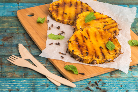 Grilled pineapple slices on wooden table.