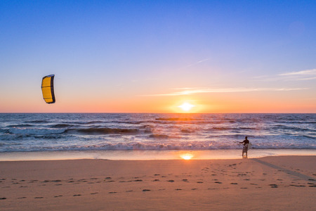 Kite surfer watching the waves at sunset in Portugal.の写真素材