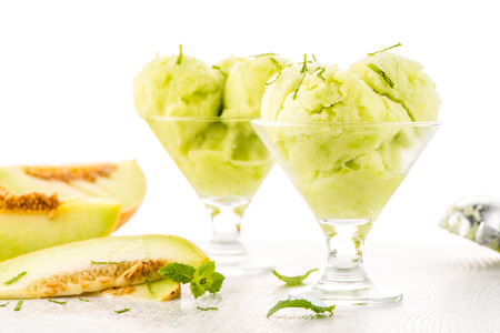 Close up of melon flavored ice-cream with mint and melon on a white table.の写真素材