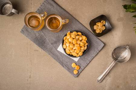 Tasty lupins in metal mug and glass of beer on wooden table top.