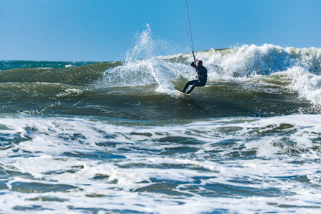 Kitesurfer riding ocean waves on a bright sunny day.の写真素材