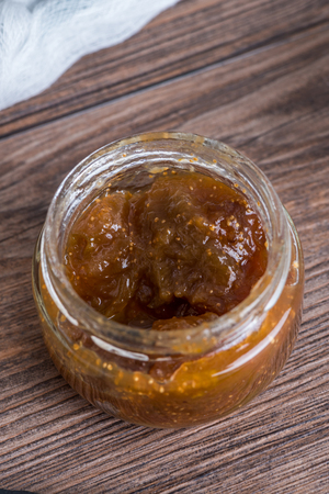 Glass jar full of fig jam on wooden background.の写真素材