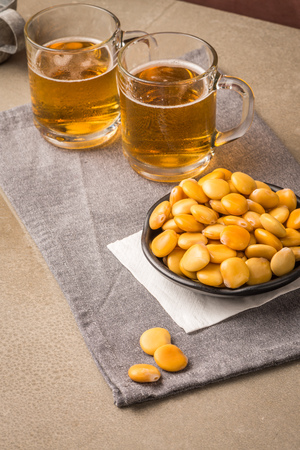 Tasty lupins in metal mug and glass of beer on wooden table top.の写真素材