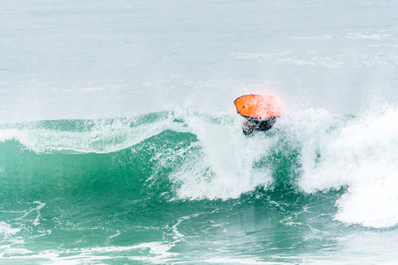 Bodyboarder surfing ocean wave on a sunny day.