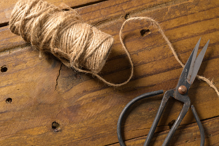 Old-fashioned scissors cutting piece of garden twine on brown wooden  background.の写真素材