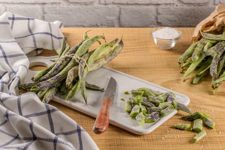 Heap of green beans on a rustic wooden table top view. Cutting board with green beans
