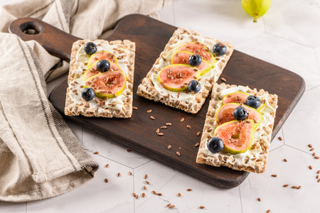 Canape or crostini with multigrain  crispread with cream cheese and fresh fig slices on a wooden...