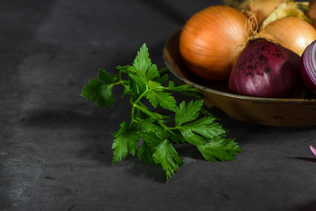 Fresh whole onions in assorted colors and parsley in a small rustic frying pan on kitchen counter top.の写真素材
