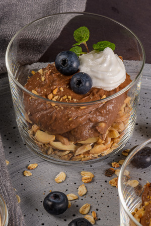 Glass cups of chocolate and chestnuts mousse with roasted almonds and oats decorated with black berries and mint leaves.の写真素材