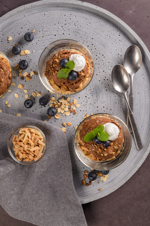 Glass cups of chocolate and chestnuts mousse with roasted almonds and oats decorated with black berries and mint leaves.の写真素材