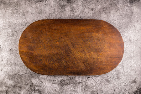 Oval shaped wood cutting board on dark concrete background. Top view with copy space for text.の写真素材