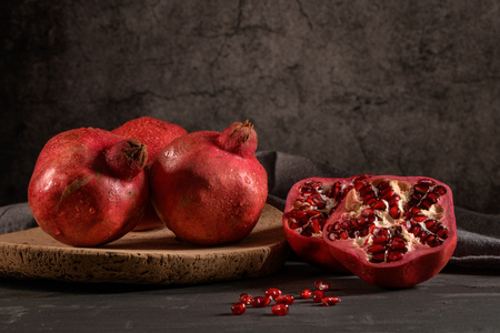 Ripe pomegranate fruit and pomegranate seeds on dark background, close-up. Healthy vegetarian antioxidant organic diet foodの写真素材