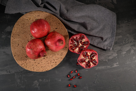 Ripe pomegranate fruit and pomegranate seeds on dark background, close-up. Healthy vegetarian antioxidant organic diet foodの写真素材