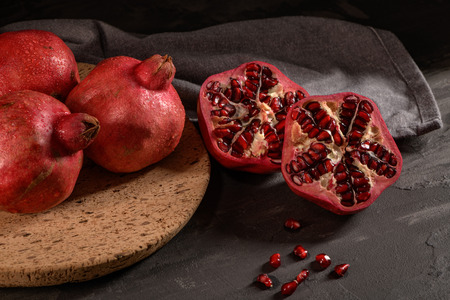 Ripe pomegranate fruit and pomegranate seeds on dark background, close-up. Healthy vegetarian antioxidant organic diet foodの写真素材