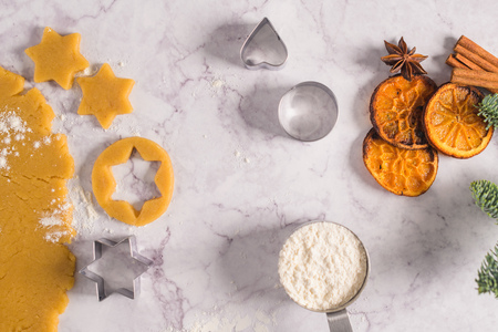 Raw dough for christmas cookies and cookie cutters on marble surface.