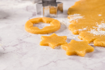 Raw dough for christmas cookies and cookie cutters on marble surface.の写真素材