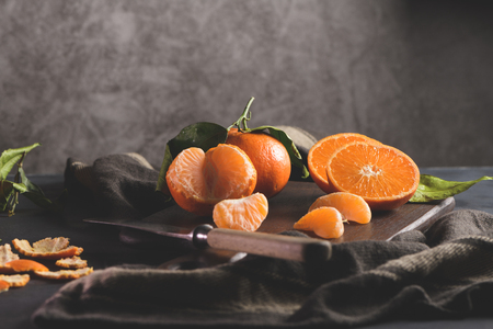 Fresh mandarin oranges or tangerines with leaves on textured dark backgroundの写真素材